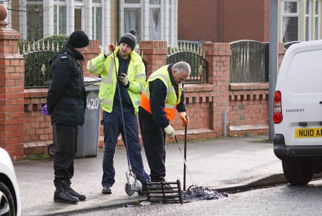 A police officer looks on as two council workers search the drains in Lytham Road, South Shore, close to where a man was stabbed