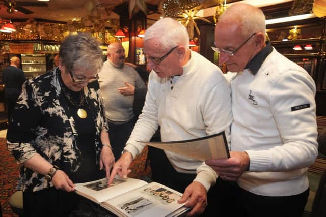 Members Barry Horton (centre) and Graham Ashfield show Maureen Pitchford (whose husband was in the group) a photo album.