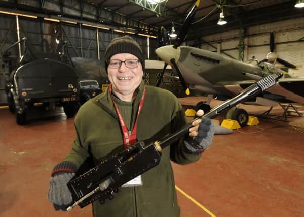 Air museum volunteer Paul Lomax with a Browning machine gun as used in a spitfire