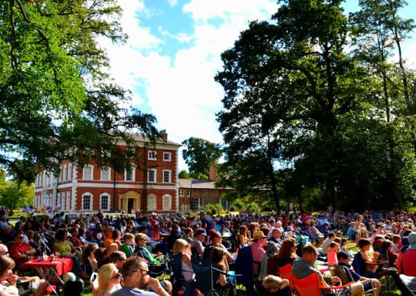 A packed audience watching an outdoor performance at Lytham Hall
