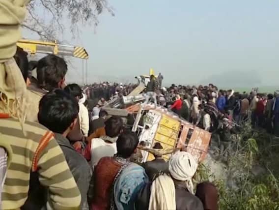 People gather at the site where a truck loaded with sand collided with a school bus in the northern Indian state of Uttar Pradesh