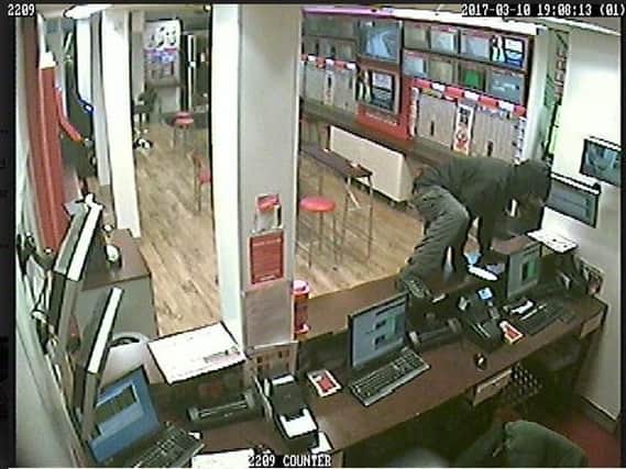 CCTV of the raider climbing over the counter at Ladbrokes in Blackpool