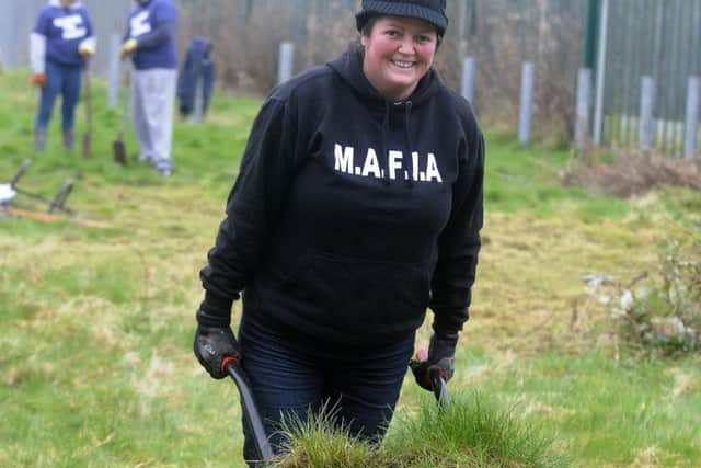 Members of Mereside MAFIA and staff from William Hill help clean derelict land for a new orchard.  Pictured is Rev Linda Tomkinson.