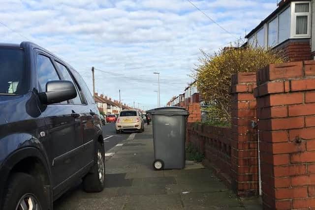 A wheelie bin and a car parked on the pavement are some of the obstacles faced by blind and visually impaired pedestrians