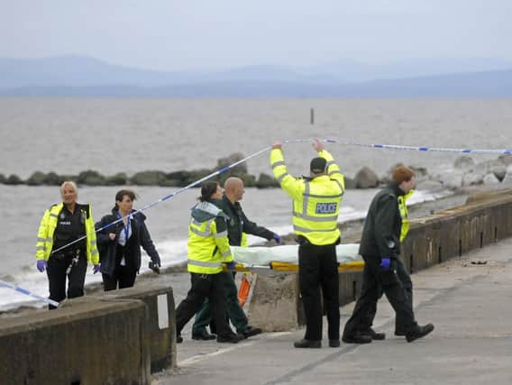 Police and ambulance crews carry a stretcher off the beach at Rossall