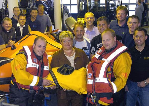 Debbie Hales presents dry suits and lifejackets to BLACKPOOL RNLI crewman Peter Barnes (left) and Shaun Wright watched by colleagues and her sons Michael and Matthew.