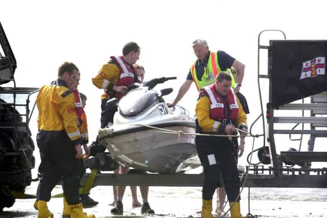 The jet ski, with damage visible on the right bow, is brought out of the water