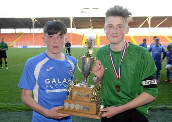 The captains of St Bede's and St George's both have a hand on the Harry Johnston Cup