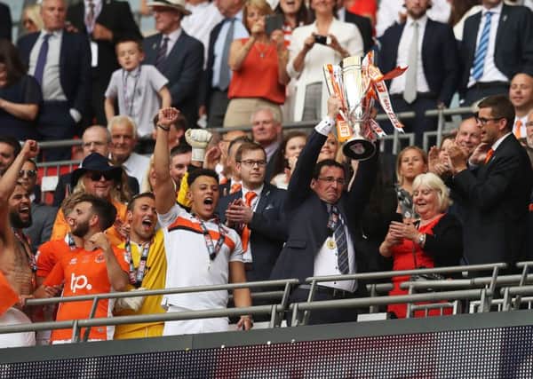 Blackpool manager Gary Bowyer lifts the trophy at Wembley. Owen Oyston is visible in the bottom left