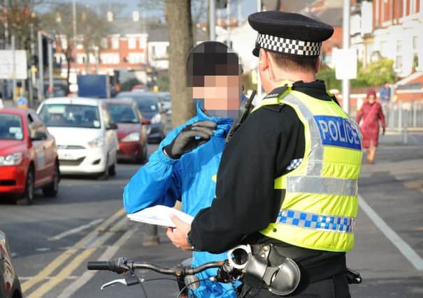 A policeman talks to a cyclist caught riding on the pavement on Whitegate Drive.