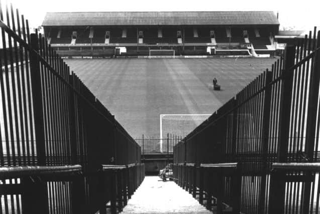 The view from the Kop at Blackpool Football Club Ground , Bloomfield Road showing the railings installed to keep rival fans apart and a 
lone groundsman hard at work mowing the pitch, in 1975