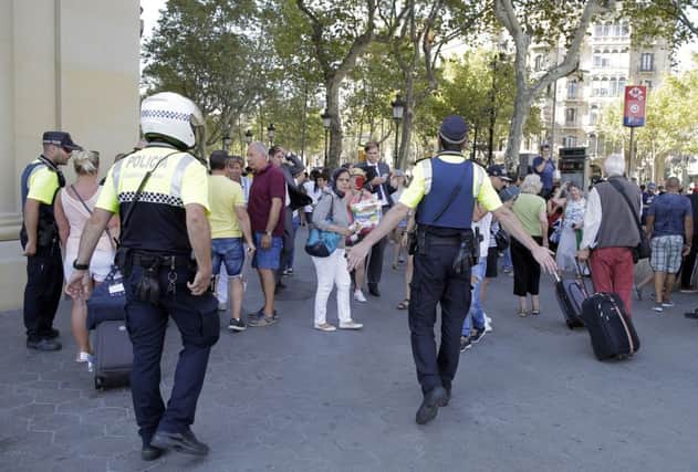 Police officers tell members of the public to leave the scene in a street in Barcelona, Spain