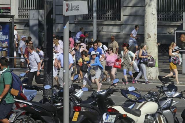 People flee the scene in Barcelona, Spain, Thursday, Aug. 17, 2017 after a white van jumped the sidewalk in the historic Las Ramblas district, crashing into a summer crowd of residents and tourists and injuring several people, police said. (AP Photo/Oriol Duran)