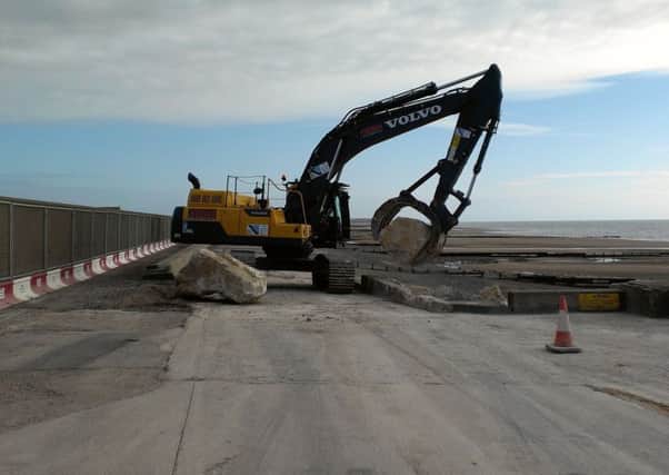 Digger moving rocks to form sea wall at Rossall