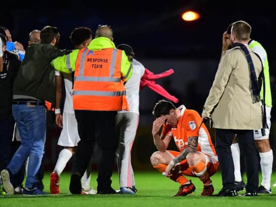 Callum Cooke kneels down as the Boreham Wood fans invade the pitch