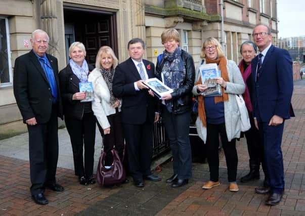 Louise Martin of the Friends of Lytham Institute and Library present their petition for the restoration of servuces to Lytham Library to Lancashire County Council cabinet membetr Peter Buckley, with supporters and other county councillors looking on