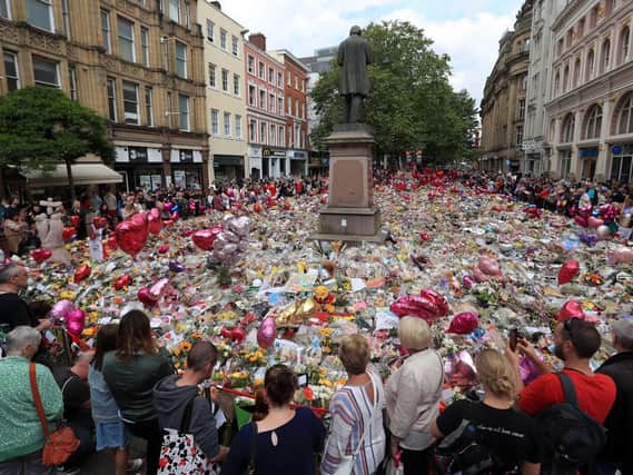 People look at flowers and tributes left in St Ann's Square in Manchester following the Manchester Arena terror attack