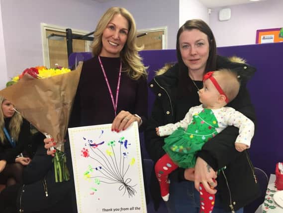Registrar, Dawn Titherington, receives a thank you bouquet from Rachel Cook and baby, Sienna Miller.
