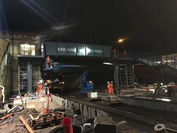 Members of Network Rails Orange Team lift the new footbridge into place at Kirkham station which connects to the new platform being built there