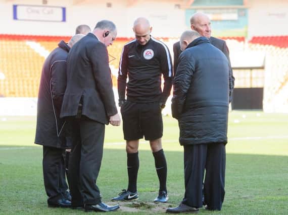 The referee inspects a sink hole at Doncaster