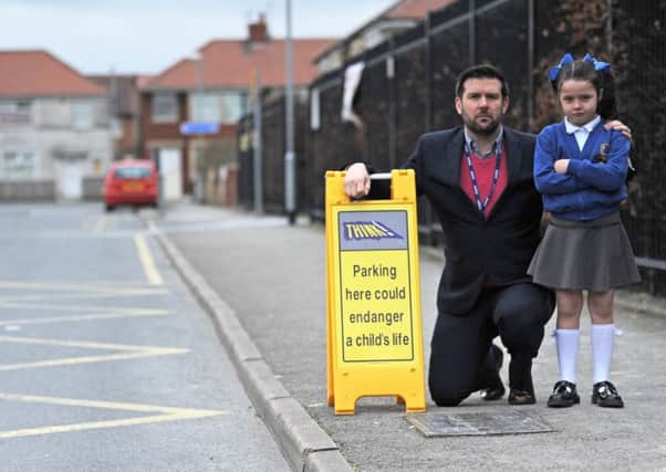 Headteacher at Flakefleet Primary School, Dave McPartlin, is having to put plastic signs outside the school due to parents parking on the road and pavement.  He is pictured with 7-year-old Naomi Cawley.