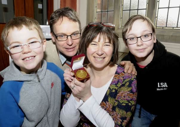 Elizabeth Dee shows off her Swimarathon medal to  husband Justin and sons Oliver and William