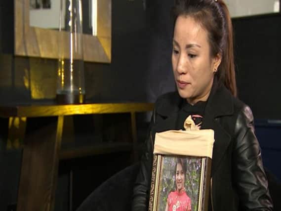 Quynh, holding a framed photo of Quyen