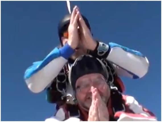 Archdeacon of Lancaster, wearing red and white, praying during his parachute jump