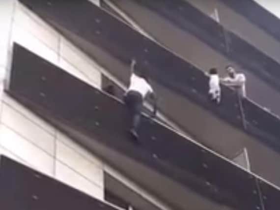 Video still of the moment the man climbs to save the dangling toddler